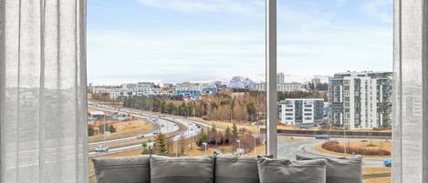 A view from a window with a cityscape, including roads and buildings, and a seating area with cushions.