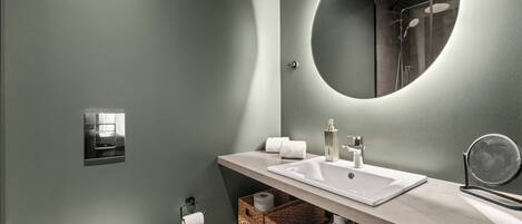 A modern bathroom with a large mirror, a sink, and a shower.