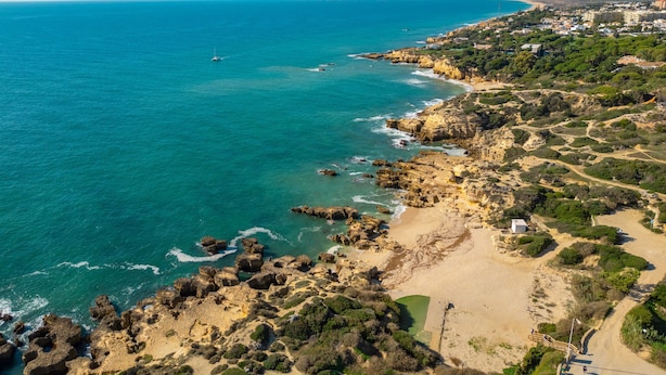 An aerial view of a coastal area with rocky terrain, a sandy beach, and a clear blue sea. - Villa Azzurra (Albufeira)
