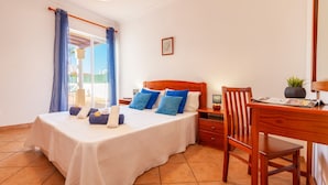 A bedroom with a bed, a desk, a chair, and a window with curtains. - Villa Azzurra (Albufeira)