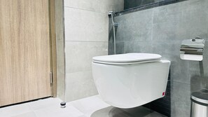 A modern bathroom with a white toilet, a shower, and a toilet paper holder. - Sunday Sheikh Zayed Road Concord Tower Studio by Belvilla (Dubai)