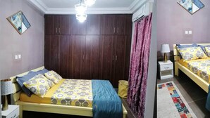 Une chambre à coucher avec un lit, une armoire, une table de chevet et une lampe.
