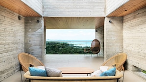 A modern interior with a view of the sea, featuring wicker furniture and a wooden ceiling. - ILUVIO RESORT MOTOBU (Motobu)