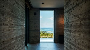 A hallway with wooden walls leading to a balcony with a view of the ocean. - ILUVIO RESORT MOTOBU (Motobu)