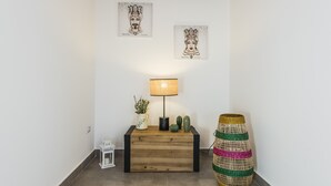 Une console en bois ornée d’une lampe, d’une petite lanterne blanche et d’un vase décoratif contenant des plantes. Deux œuvres d’art encadrées sont accrochées au mur au-dessus de la console.