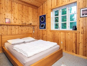 A wooden-paneled room with a bed, a window, and a sign on the wall. - 4 Star Holiday Home in Kolind (Kolind)