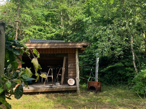 A wooden cabin with a porch, surrounded by dense forest. - 4 Star Holiday Home in Kolind (Kolind)