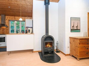 A modern kitchen with a wood-burning stove, a wooden cabinet, and a window with a view of greenery. - 4 Star Holiday Home in Kolind (Kolind)