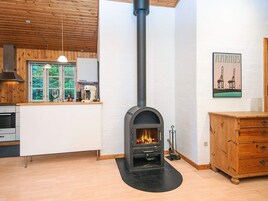 Una cocina moderna con estufa de leña, un armario de madera y una ventana con vistas a la vegetación.