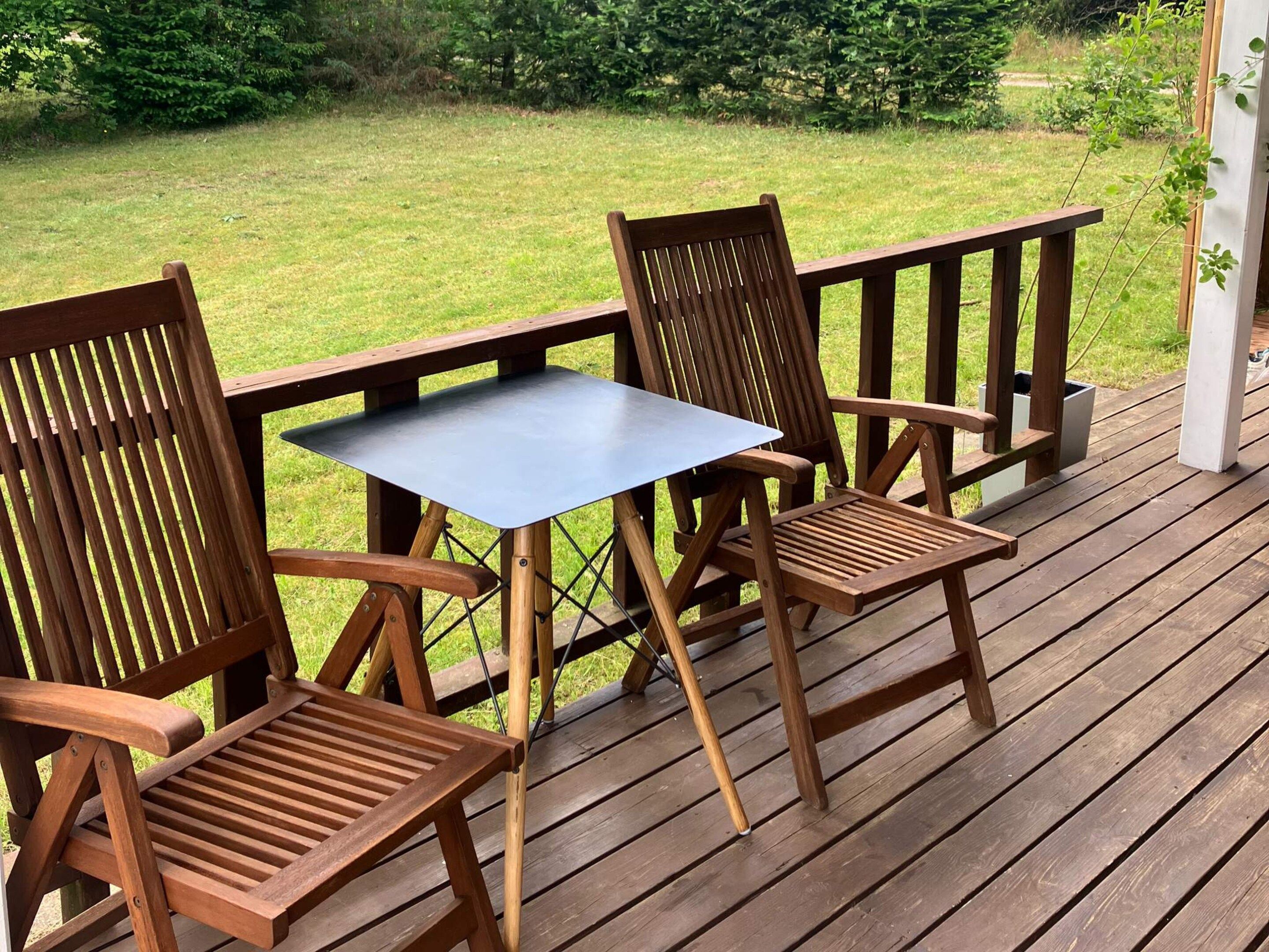 Una terraza de madera con una mesa y dos sillas.