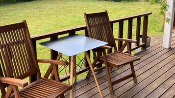 Una terraza de madera con una mesa y dos sillas.