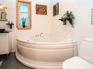 A bathroom with a freestanding bathtub, a window, a mirror, and a wall-mounted shelf with plants. - 4 Star Holiday Home in Kolind (Kolind)