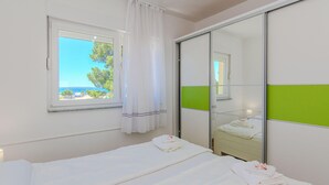 A hotel room with a bed, a window with a view of the sea, a mirror, and a green panel on the wall. - Awesome apartment in Privlaka with house sea view (Privlaka)