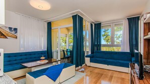 A modern living room with a sofa, a small table with a plate of fruit, and a television. - Awesome apartment in Privlaka with house sea view (Privlaka)