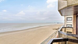Une vue sur la plage depuis un balcon, avec un ciel dégagé.