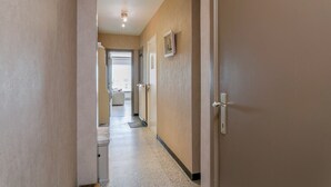 Un corridoio con una porta sulla destra, un quadro appeso al muro e uno scorcio di una stanza in fondo.