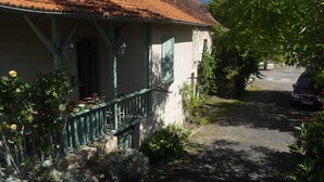 A house with a porch, a stone wall, and a car parked in the background.