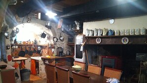A rustic kitchen with wooden furniture, a fireplace, and various kitchen utensils.