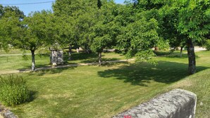 A well-maintained park with a stone wall, lush green grass, and trees.