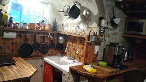 A rustic kitchen with a wooden countertop, a sink, and various cooking utensils hanging above.