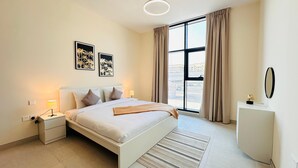 A modern bedroom with a bed, bedside tables, a desk, and a large window with curtains.