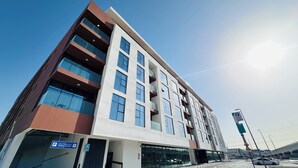 A modern multi-story building with a parking entrance sign, large windows, and a clear sky.