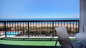 Un balcon avec vue sur une plage et une piscine.