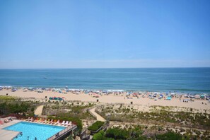 A beach with a swimming pool, sandy beach, and ocean view.