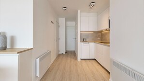 A narrow hallway with a kitchen area featuring white cabinets, a wooden countertop, and a built-in sink. - Apartment in Blankenberge by the Sea (Blankenberge)