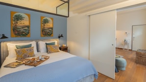 A modern bedroom with a large bed, two wall-mounted paintings, a bedside table with a lamp, and a door leading to another room. - The Printers Home 2 in Como (Como)