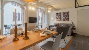 A dining area with a wooden table set for four, a sofa, and a TV mounted on the wall. - The Printers Home 2 in Como (Como)