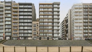 Una spiaggia assolata con edifici alti, una distesa di sabbia e una passeggiata pedonale.