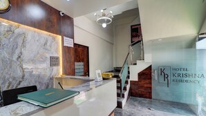 A reception desk with a marble wall, a clock, and a sign for Hotel Krishna Residency. - Hotel Krishna Residency  (Navi Mumbai)