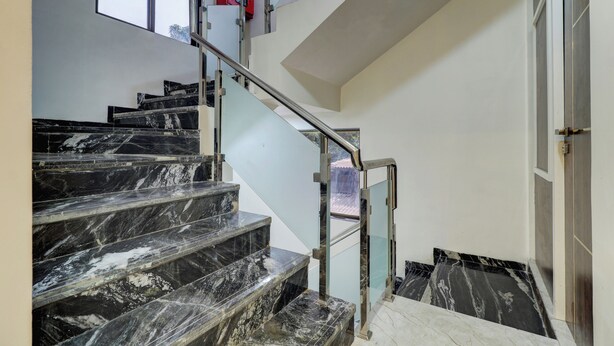 A staircase with black marble steps and glass railings. - Hotel Krishna Residency  (Navi Mumbai)