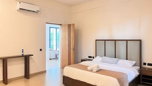 Une chambre à coucher comprenant un lit, des tables de chevet, un banc et un appareil de climatisation.