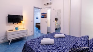 Een hotelkamer met een bed, een televisie, een nachtkastje, een lamp en een badkamer die door een open deur zichtbaar is.