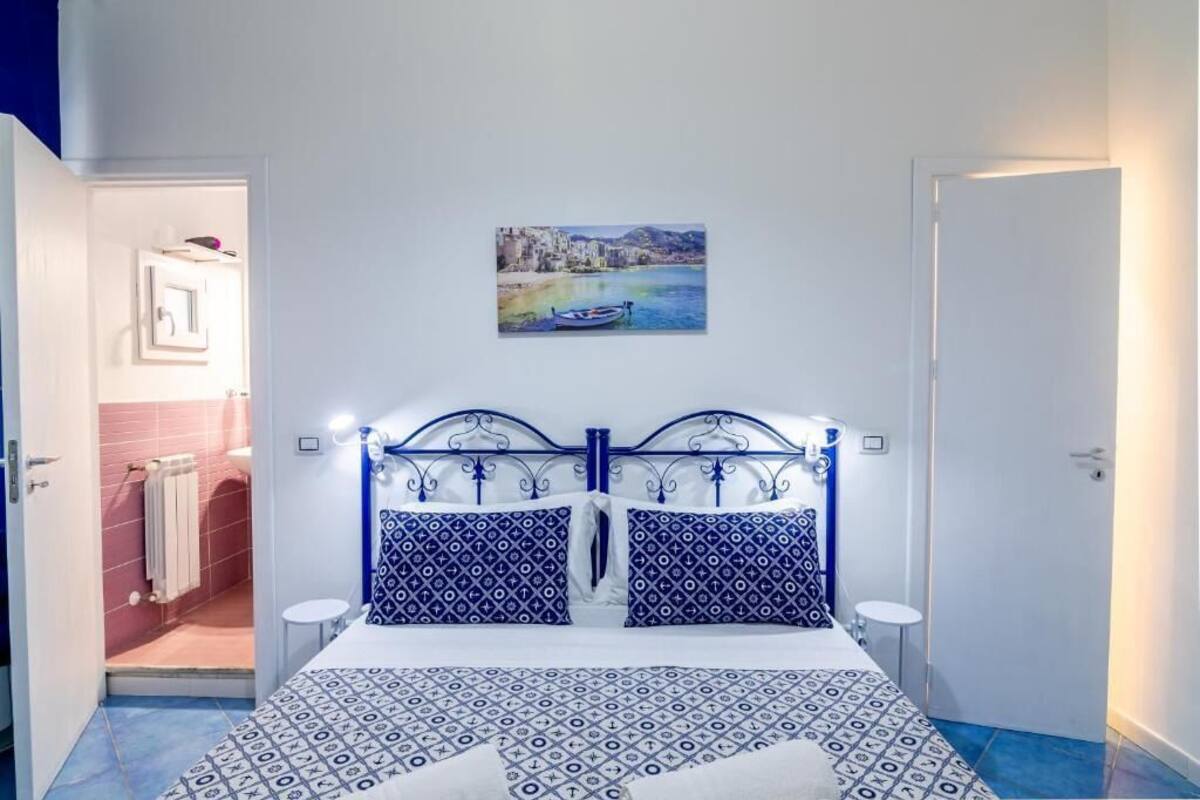 Une chambre à coucher avec un lit, un tableau, une porte de salle de bain et un mur blanc.