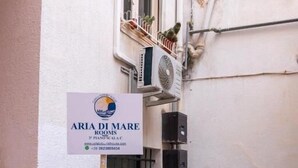 Een bordje met de tekst 'ARIA DI MARE ROOMS', een telefoonnummer en een website.