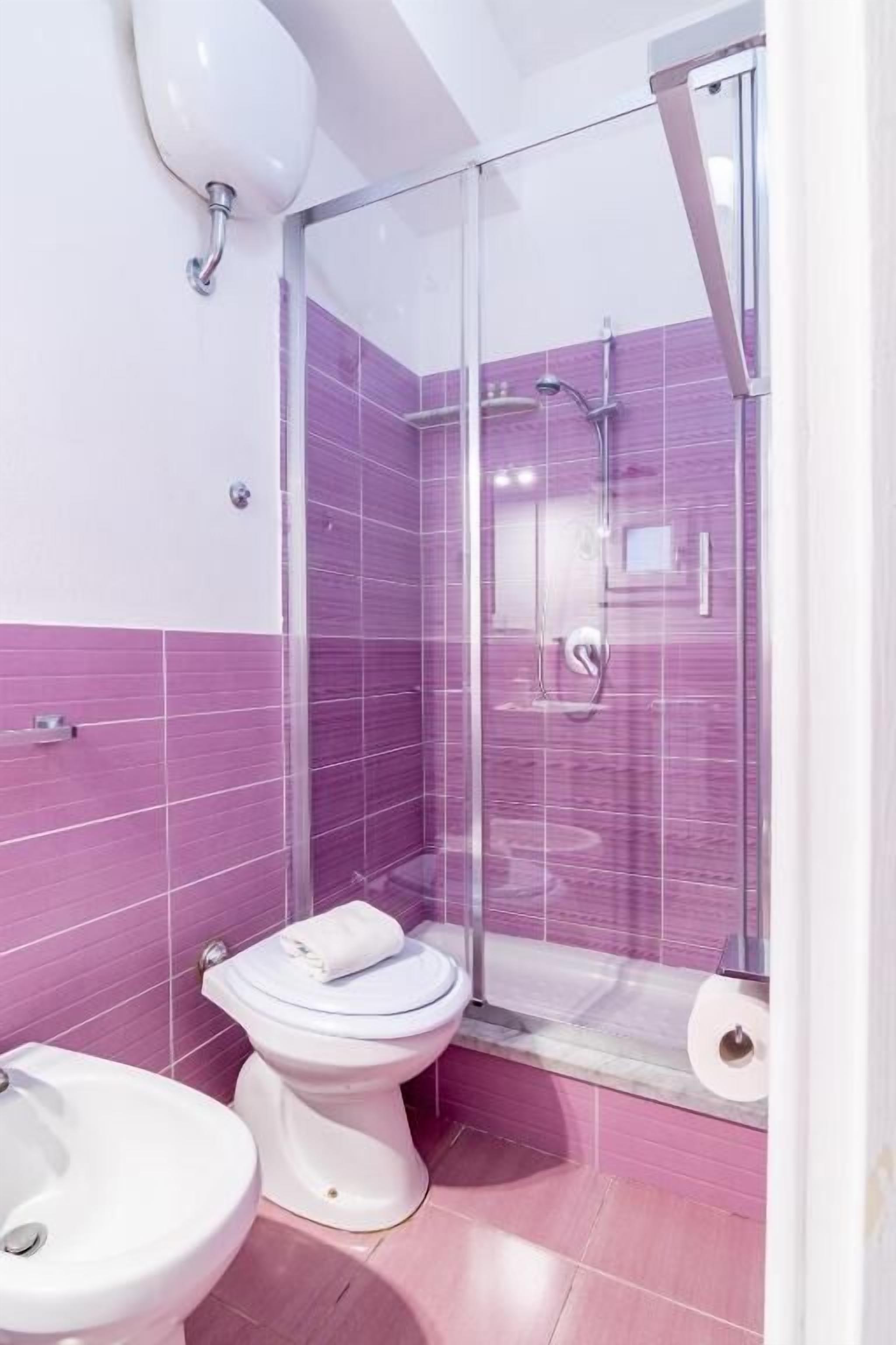 A bathroom with a glass-enclosed shower, a toilet, and a bidet.
