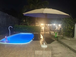 A swimming pool with a water fountain, surrounded by a tiled patio area. - House on Maranduba Beach - Ubatuba (Rio da Prata Ubatuba)