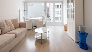 A modern living room with a sofa, a small round table, and a cabinet. - Apartment With Side sea View (Ostend)
