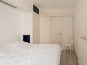 Ein Schlafzimmer mit einem Bett, einem Sessel, einer Tür und einer Heizung.