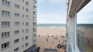 A view of a beach from a building with multiple floors and a parking area in the foreground. - Apartment With Side sea View (Ostend)