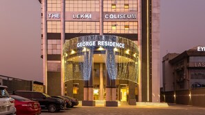 Het LeKki Coliseum met een George Residence ingang, gekenmerkt door een modern architectonisch ontwerp met grote kolommen en verlichte signage.
