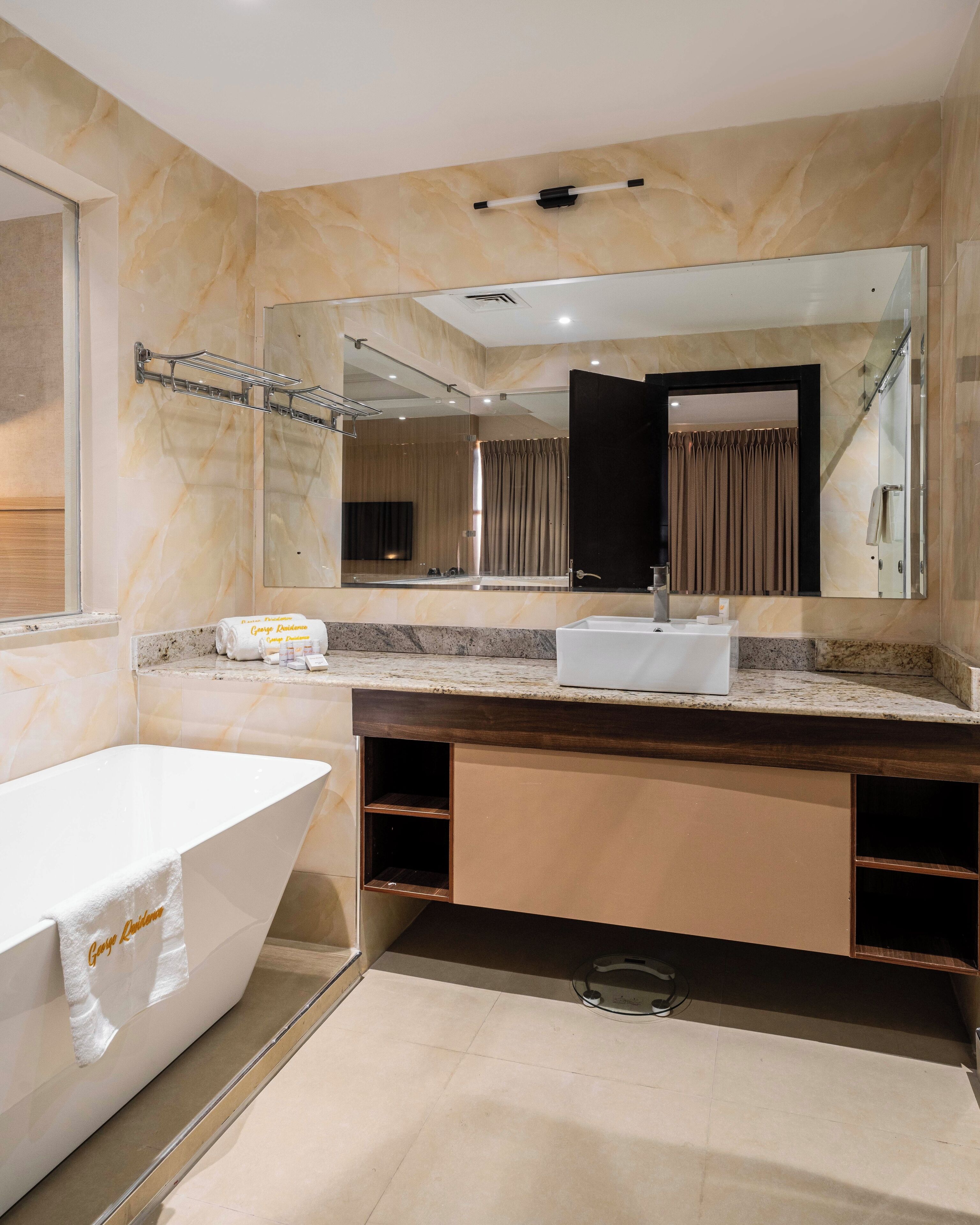 Un baño moderno con una bañera independiente, un espejo grande y un tocador con lavabo.