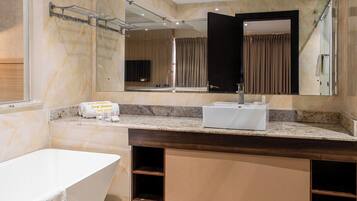 Un baño moderno con una bañera independiente, un espejo grande y un tocador con lavabo.