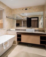 Un baño moderno con una bañera independiente, un espejo grande y un tocador con lavabo.