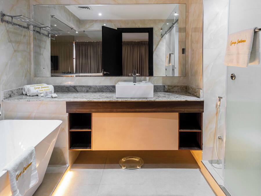 Une salle de bain moderne avec un grand miroir, une baignoire blanche, un meuble-lavabo et un espace douche.
