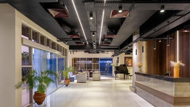 Een moderne hotellobby met een gepolijste vloer, een receptiebalie, een zithoek en grote ramen.