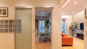 A modern living room with a sofa, a dining table with chairs, and a kitchen area visible through an open door. - HouSmart Treves 2 (Bologna)